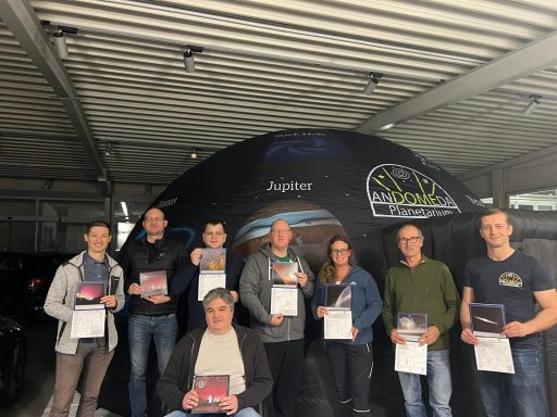 Gruppe von sieben Personen mit Urkunden vor einem großen Zelt.